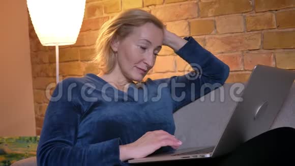 在笔记本电脑上观看电影的白种人女性的特写镜头面部表情有趣地坐在电脑上视频的预览图
