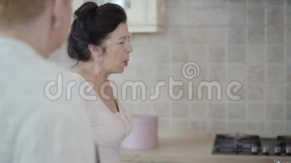 中年成熟的女人在家里的厨房里聊天女士给她的朋友讲故事视频的预览图