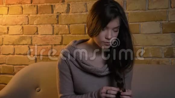 年轻美丽的白种人女孩做一个辫子平静地看着镜头上的布里克肯墙背景视频的预览图