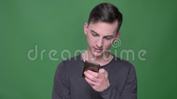 年轻英俊的白种人男性特写镜头在电话里发短信看着镜头笑着背景视频的预览图