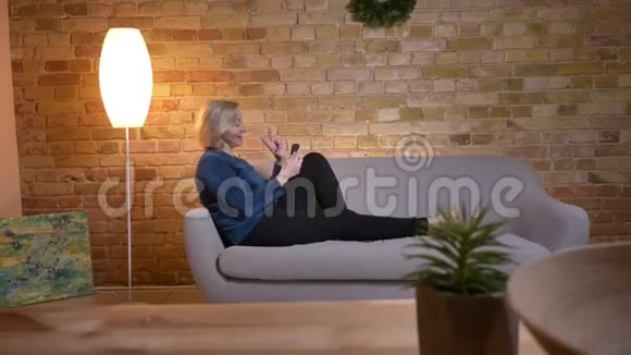 高白种人女性坐在沙发上通过视频电话愉快地交谈的特写镜头视频的预览图