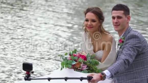 男人把他满意的女人拍在自拍棒上人们漂浮在船上视频的预览图