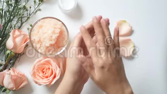 4K自然护肤概念女人把白色奶油涂在她的手上白色背景上有一罐霜盐水疗擦洗视频的预览图