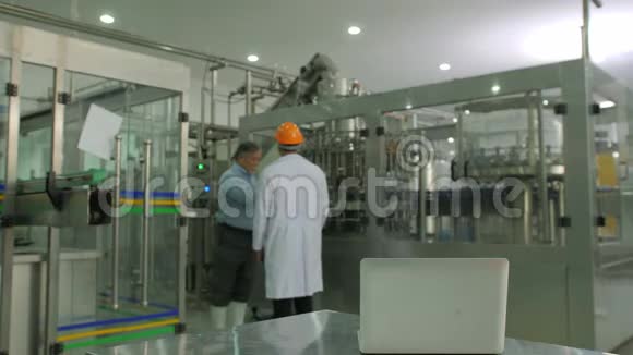 高级经理与机械工人检查生产计划与瓶子生产线在后台视频的预览图