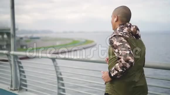 非洲裔美国运动员在城市地区的桥梁上缓慢奔跑视频的预览图