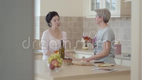 两个成熟的女朋友在厨房里见面聊天黑发女孩做着手势说着什么视频的预览图
