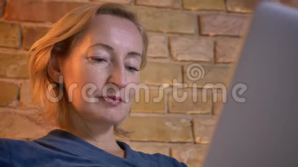 在舒适的室内公寓里一位使用平板电脑拍摄的白种人年长女性的特写镜头然后直视镜头视频的预览图