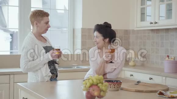 成熟的女性在家中交流站在厨房的现代餐桌旁一位女士带着真诚的微笑说祝酒词视频的预览图