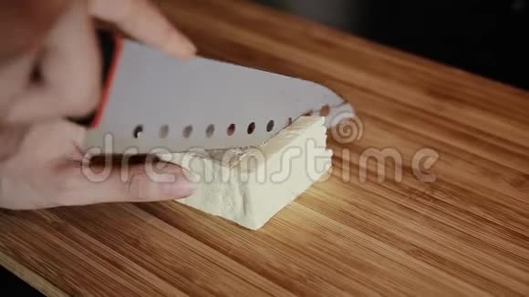 女人在木制厨房板上把豆腐切成小块回家视频的预览图
