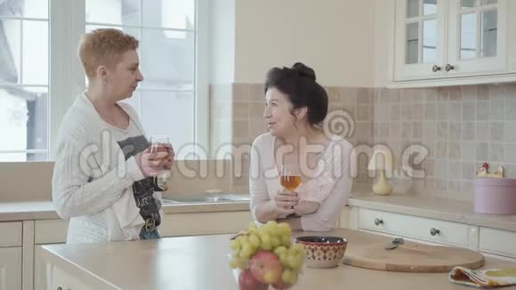 两位迷人的中年成熟女性在厨房的餐桌上聊天和喝酒高级妇女视频的预览图