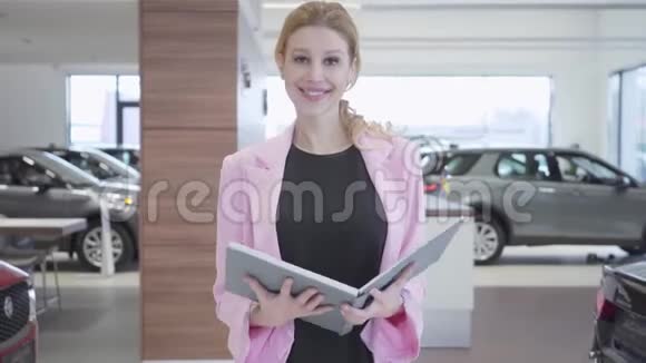 一个穿着商务服的微笑推销员在一家汽车经销店会见来访者的肖像那个女孩要视频的预览图