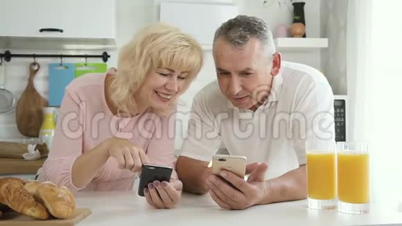老人教退休妻子在厨房使用智能手机视频的预览图