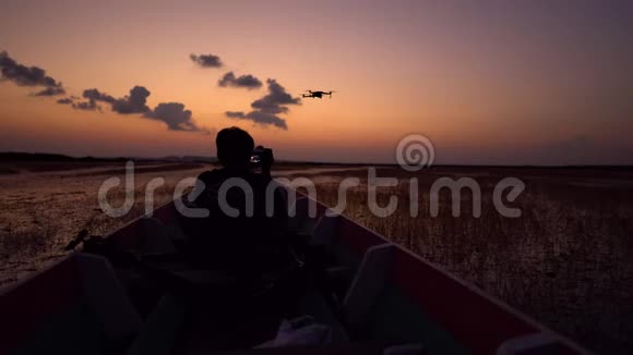摄影专家在日落时分在船上拍摄一架无人机美丽的灯光自然景观视频的预览图