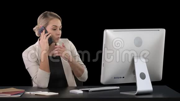 迷人的年轻女子在手机上说话微笑着坐在办公室的工作场所看着她视频的预览图