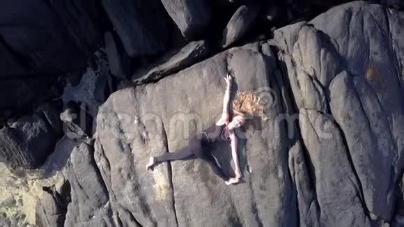 穿黑色运动服的女孩在灰色岩石悬崖上伸腿视频的预览图