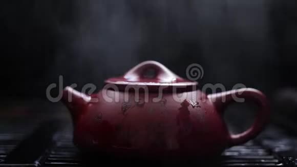 热泥茶壶蒸汽在黑色用象形文字浇灌红棕色茶壶视频的预览图