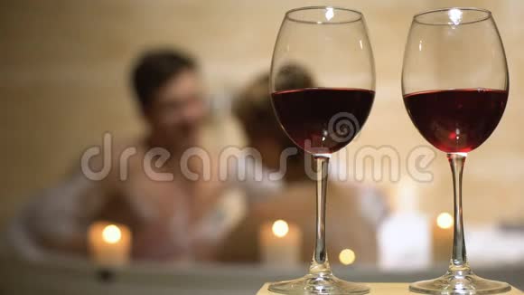 红葡萄酒杯站在心爱夫妇的背景下在浴缸里享受着视频的预览图