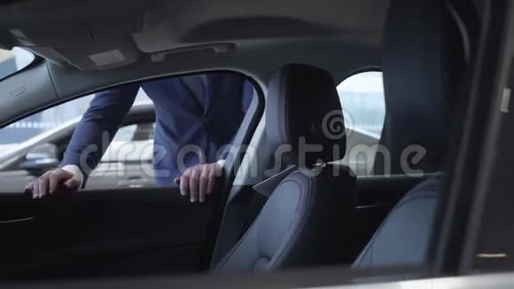 西装革履的商人看着车里然后打开车门漂亮的女人坐在车里检查它视频的预览图