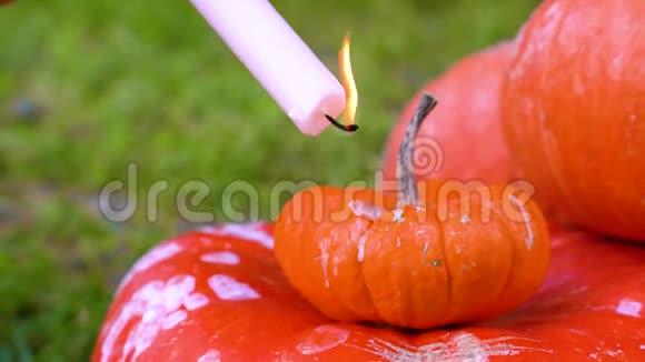 女孩手里拿着燃烧的蜡烛融化的蜡滴在一个橙色的南瓜上万圣节感恩节秋天收获视频的预览图