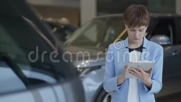 一幅自信的漂亮女人穿着正式服装的肖像她在车展上用平板电脑检查汽车女士检查车视频的预览图