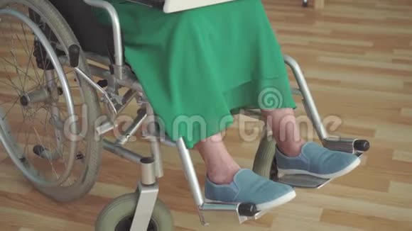 轮椅上残疾的快乐微笑的老年妇女使用笔记本电脑视频的预览图