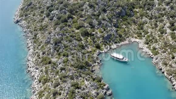 一艘白色游艇停泊在蓝色回水中的岩石海岸附近视频的预览图