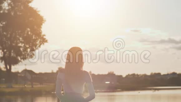 美丽的女孩在日落时在湖边的一个夏天的晚上视频的预览图