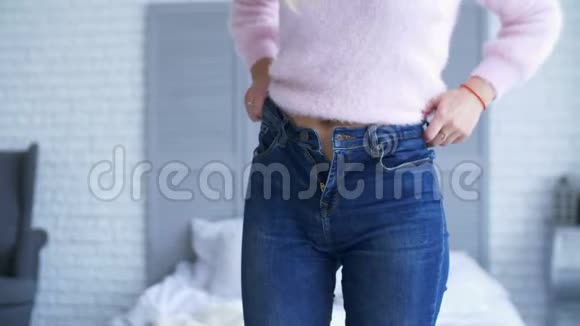 一位成年女性试图在家里拉上紧身牛仔裤视频的预览图