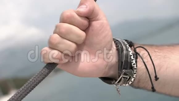 人手戴着皮手镯握在船上的海绳上视频的预览图