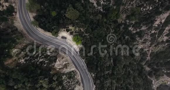 一辆黑色汽车停在一片漆黑的森林的山坡上一条路的一个拐弯处视频的预览图