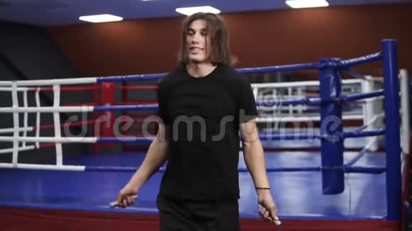 积极的长头发的白种人在拳击馆锻炼跳上黑色T恤的跳绳体育运动视频的预览图
