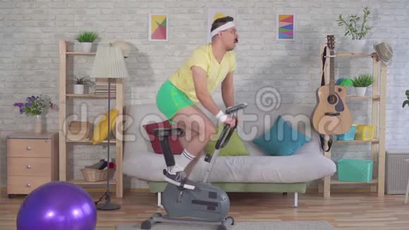 有趣的80多岁的运动健将带着胡子在家里骑着一辆静止的自行车慢悠悠视频的预览图