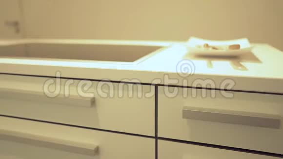 漂亮的慢动作现代厨柜白色厨房石英台面电动灶台和厨房水槽作为厨房视频的预览图