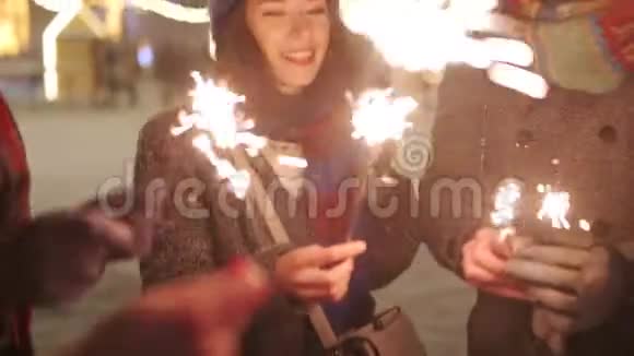 朋友们手里拿着火花挥舞女孩在圣诞前夜新年假期或生日聚会上尽情欢乐视频的预览图