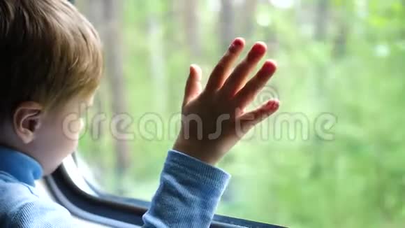 这个男孩坐火车旅行望着窗外看着窗外移动的物体手工特写视频的预览图