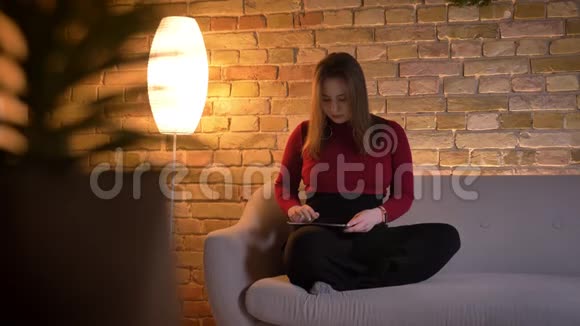 特写镜头年轻漂亮的白种人女性在平板电脑上发短信然后坐着体贴地看着相机视频的预览图