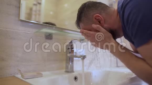 早上的卫生男人在浴室里用清水洗脸慢动作视频的预览图