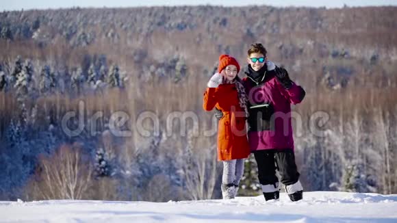 在阳光明媚的日子里快乐的库普尔向山上滑雪场的摄像机挥手冬季体育假日恋爱视频的预览图