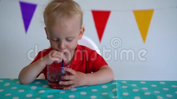 快乐的孩子用吸管从杯子里喝苹果汁万向节运动视频的预览图