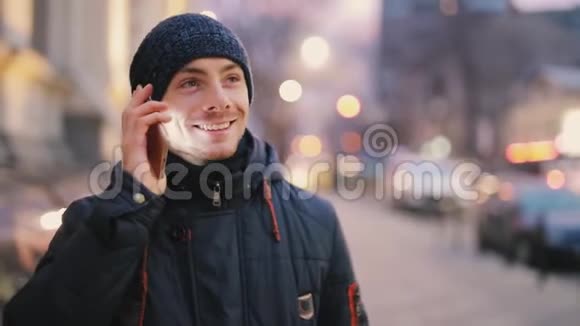 快乐的男人用智能手机在夜城里散步视频的预览图