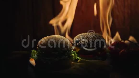 一个黑面包汉堡西红柿玉米和一个炸土豆躺在木桌上背景是黑暗中的火焰视频的预览图