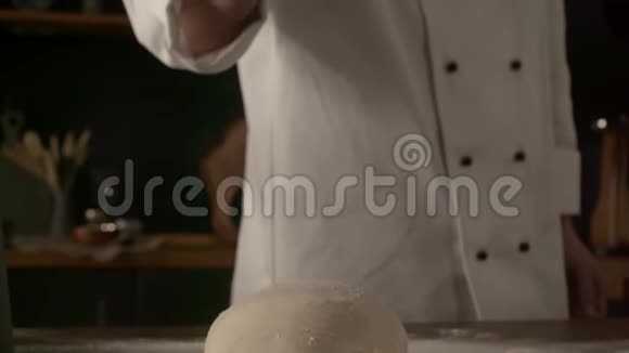 男厨师在厨房桌子上用面粉揉面团慢动作做饭视频的预览图