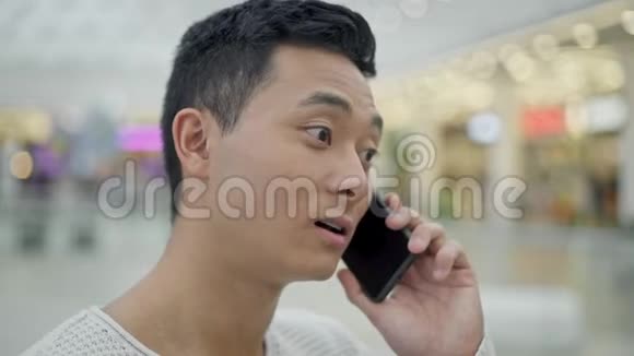 接近亚洲男性在购物中心的背景下通过电话交谈视频的预览图