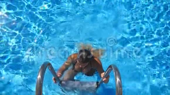 穿着泳衣从游泳池里出来的漂亮的晒黑女人年轻性感的女孩在盆里享受着暑假的清爽视频的预览图