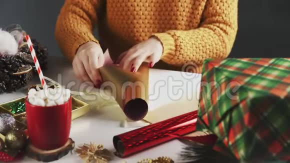 准备金纸的女人用圣诞装饰在桌子上包装圣诞礼物视频的预览图