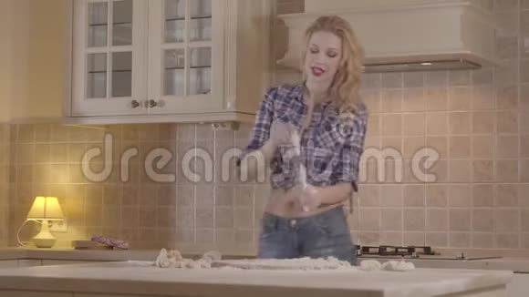 肖像诱惑女孩与一个性感的身体正在准备面团而站在厨房的桌子快乐的女孩视频的预览图