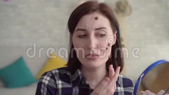 年轻沮丧的女人脸上戴着痣照镜子视频的预览图