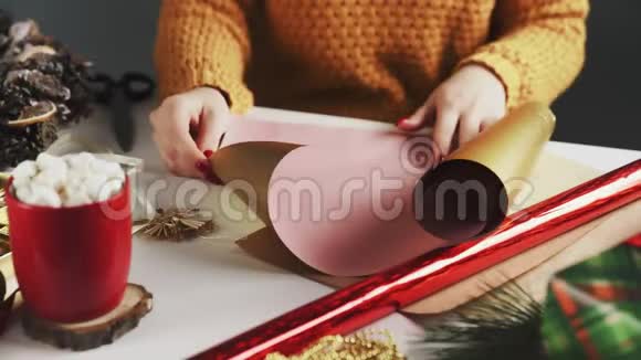 准备金纸的女人用圣诞装饰在桌子上包装圣诞礼物视频的预览图