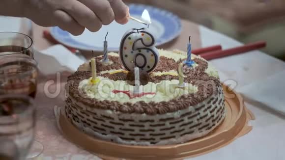 在桌上的生日蛋糕上用火柴点燃男性手上的蜡烛视频的预览图