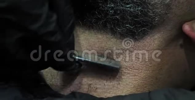 理发师用一把灰白头发的直剃须刀刮一位老人的胡子视频的预览图
